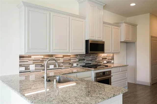 a kitchen with stainless steel appliances granite countertop a stove a microwave and a white cabinets
