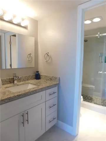 a white toilet sitting next to a bathroom sink and vanity