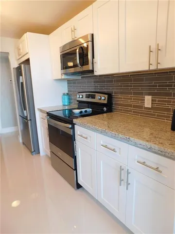 a kitchen with stainless steel appliances granite countertop a sink a stove and white cabinets