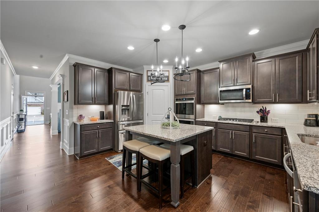 6780 Rambling Vale Dawsonville, GA 30534 - Photo 11 of 53 a kitchen with stainless steel appliances kitchen island granite countertop a stove a sink dishwasher a refrigerator and a dining table with wooden floor