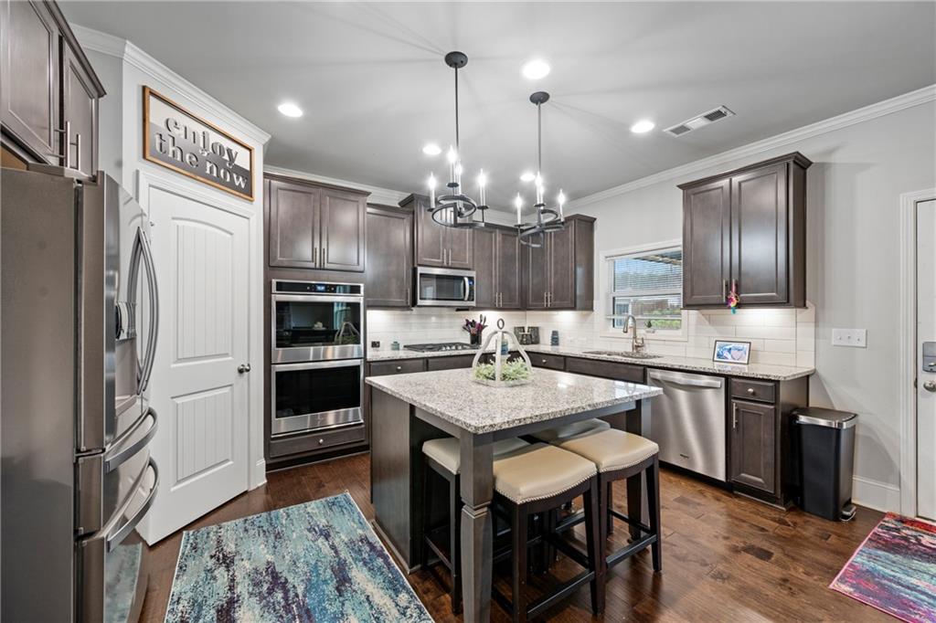 6780 Rambling Vale Dawsonville, GA 30534 - Photo 12 of 53 a kitchen with kitchen island granite countertop stainless steel appliances a sink stove and refrigerator