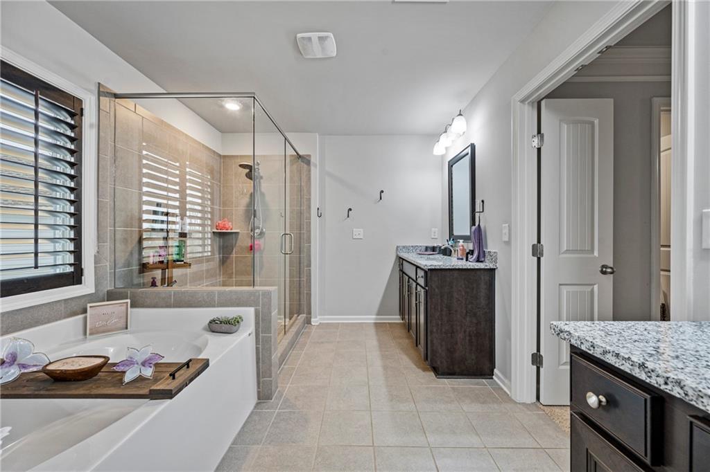 6780 Rambling Vale Dawsonville, GA 30534 - Photo 35 of 53 a bathroom with a granite countertop sink a large mirror and a bathtub