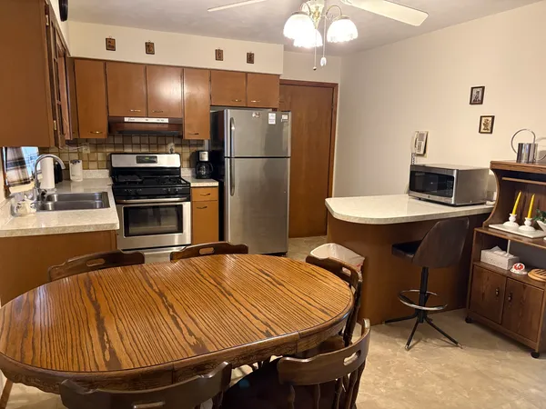 a room with kitchen island a appliances dining table chairs and a refrigerator