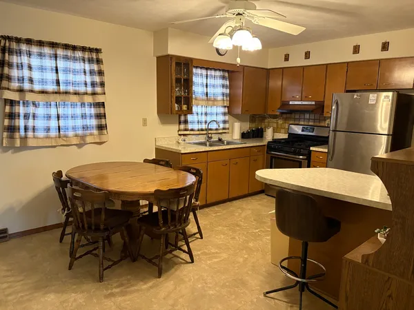 a kitchen with kitchen island a dining table chairs stainless steel appliances and cabinets