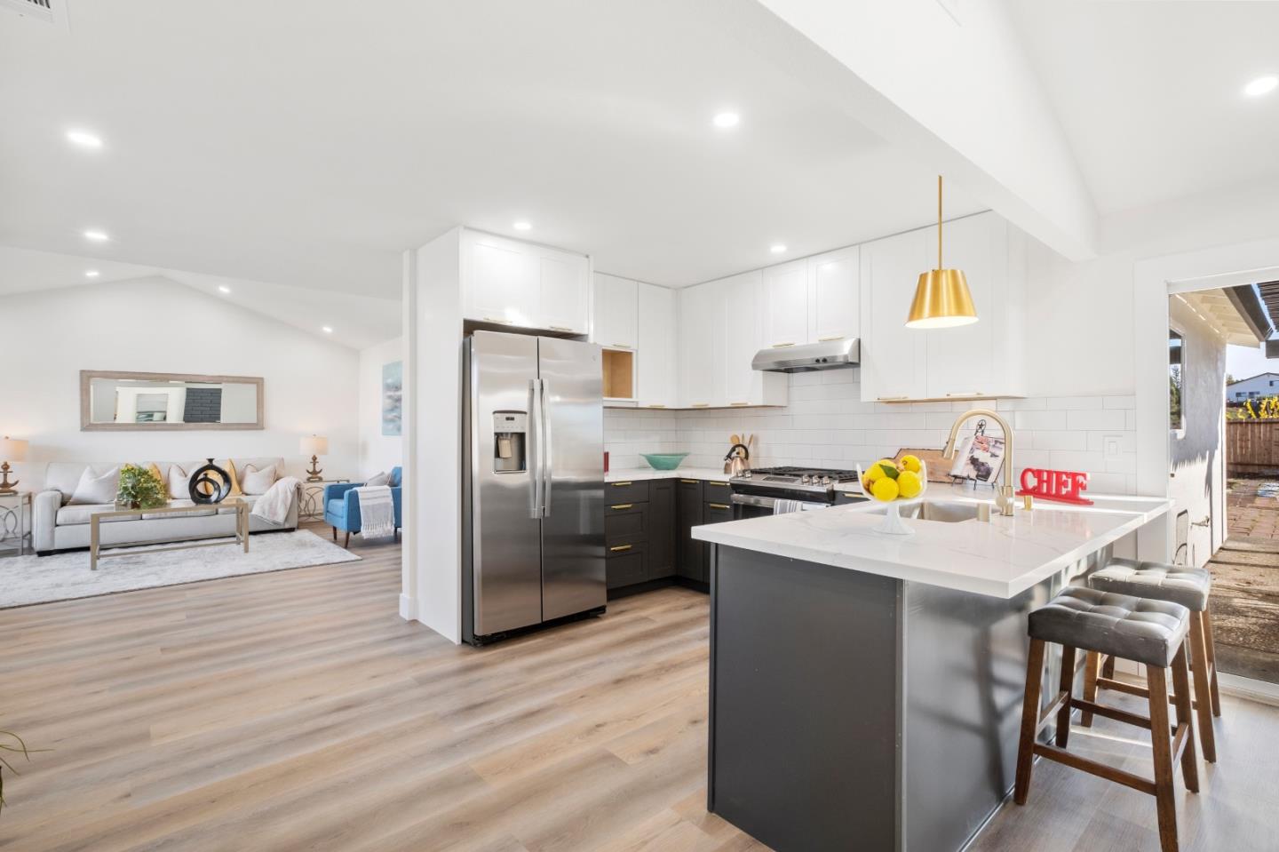 a kitchen with stainless steel appliances a stove a refrigerator a sink a dining table and chairs