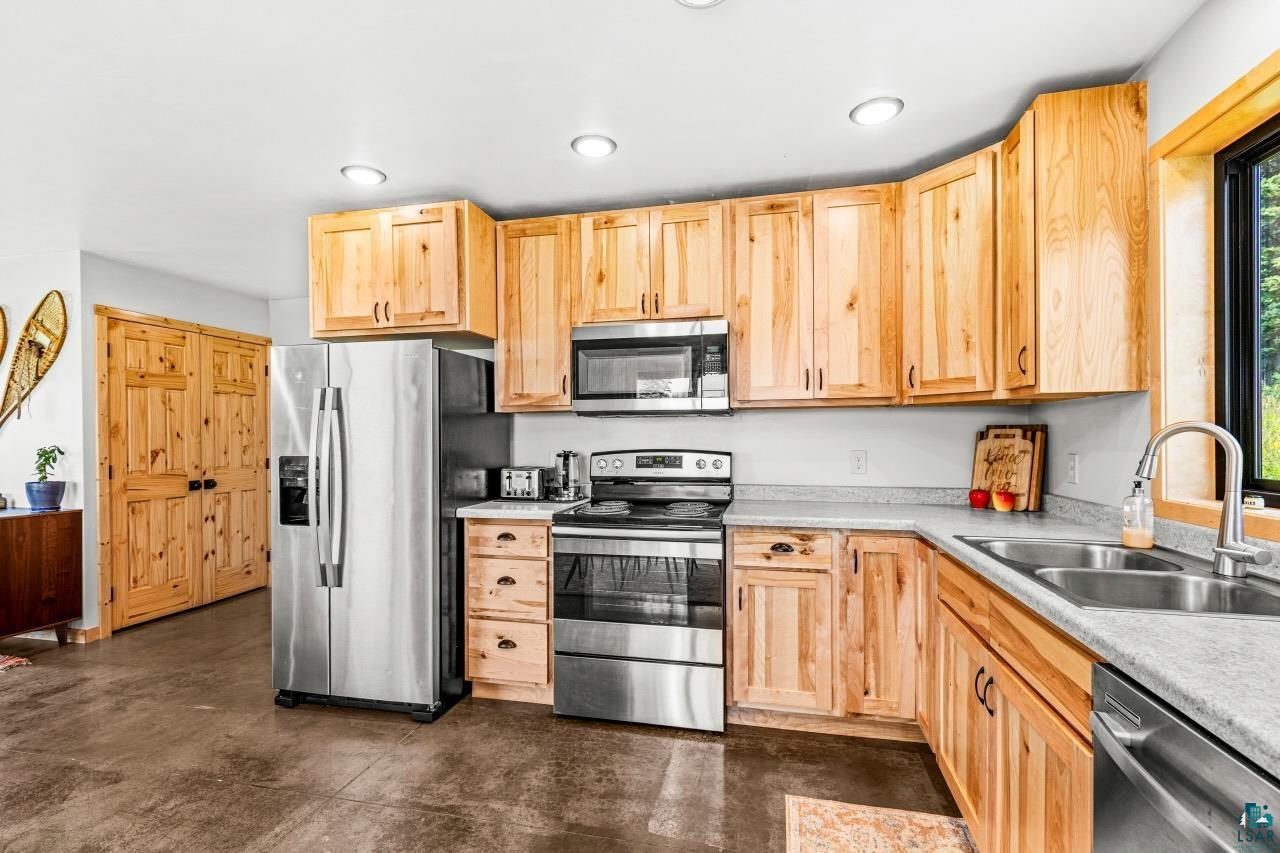 265 Mink Ranch Road Lutsen, MN 55612 - Photo 5 of 33 Kitchen with light wood cabinetry, stainless steel appliances, light-toned countertops, a double basin sink, and wood-finish flooring