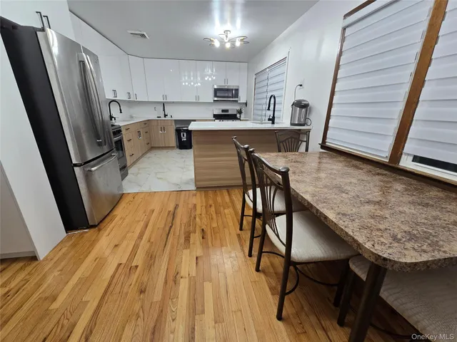 a kitchen with stainless steel appliances granite countertop a refrigerator a stove a sink dishwasher and white cabinets with wooden floor