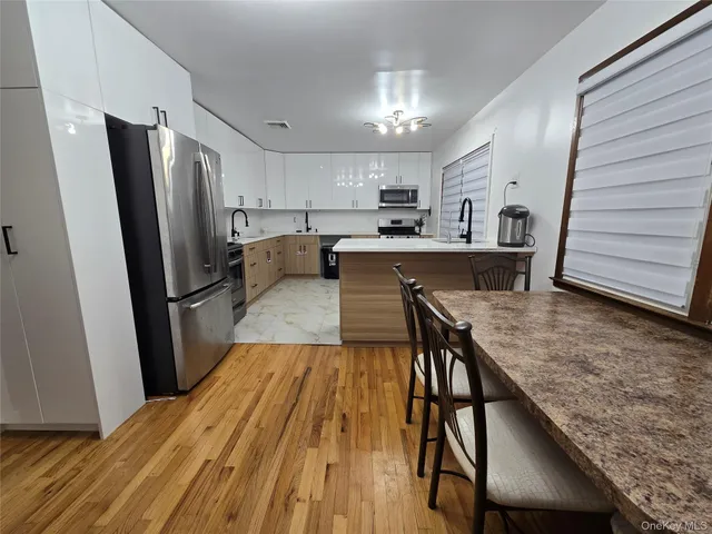 a kitchen with kitchen island a counter space a sink a refrigerator and wooden floor