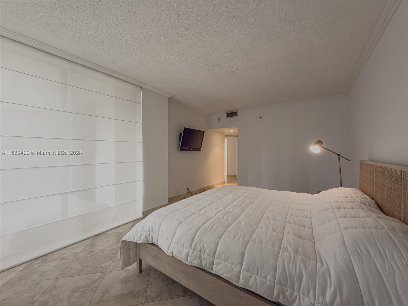 520 Brickell Key Drive, Unit A705 Miami, FL 33131 - Photo 21 of 66 a bedroom with a bed and a lamp on dresser