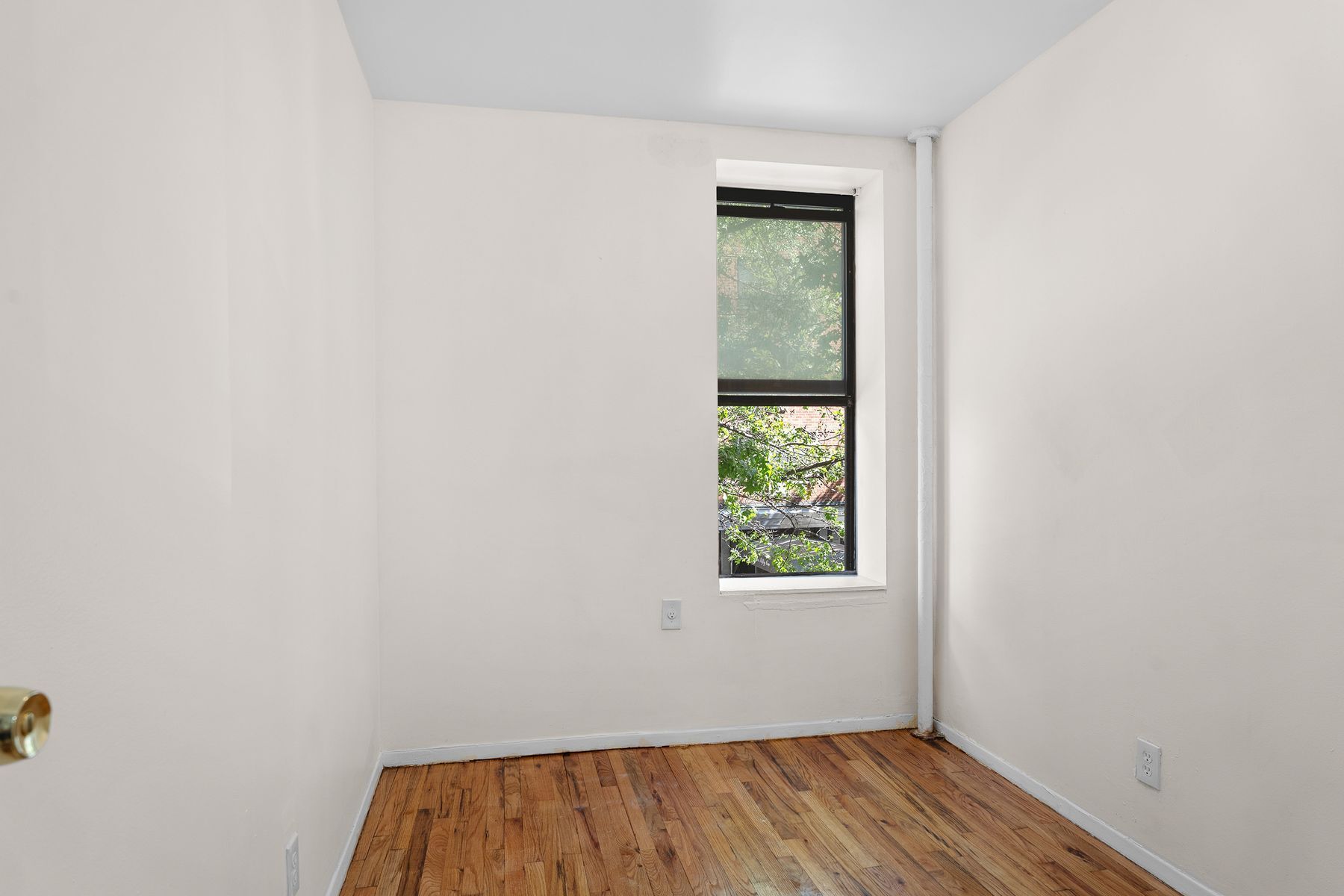 246 East 51st Street, Unit 7 Manhattan, NY 10022 - Photo 4 of 8 a view of an empty room with wooden floor and a window