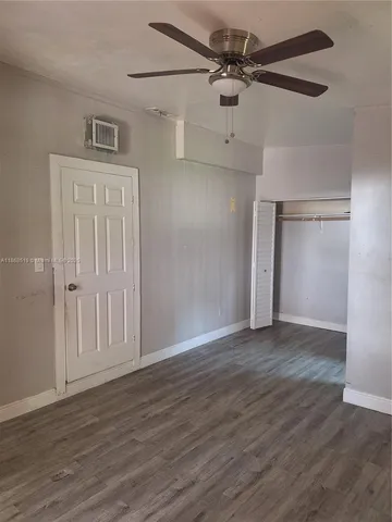 an empty room with wooden floor ceiling fan and windows