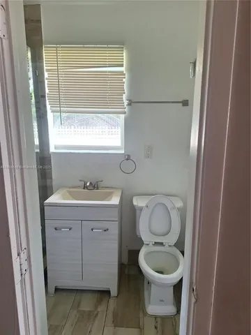 a bathroom with a granite countertop toilet a sink and a window