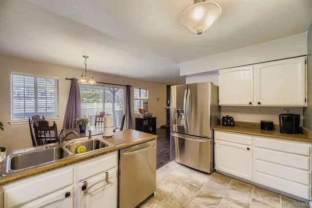 a kitchen with stainless steel appliances granite countertop a refrigerator a sink a stove and white cabinets with wooden floor