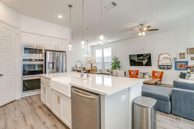 a large white kitchen with a white countertops a stove a sink and a dining table with white walls