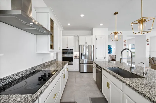 a large kitchen with granite countertop a sink a counter top space appliances and cabinets