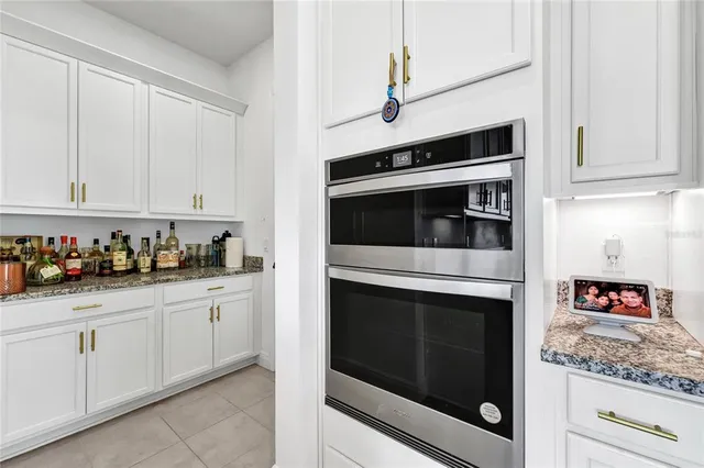 a kitchen with granite countertop white cabinets and stainless steel appliances