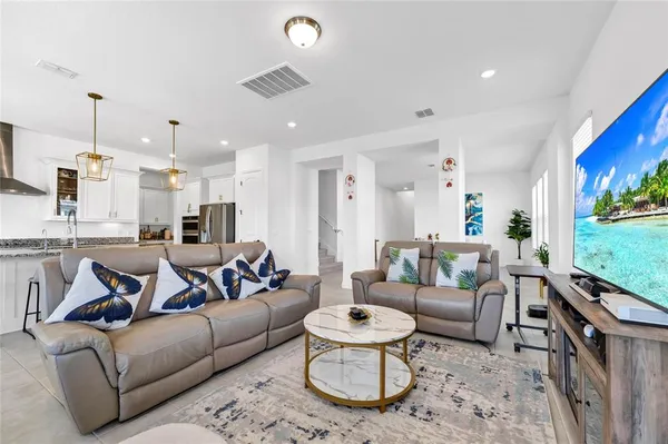 a living room with furniture kitchen view and a chandelier