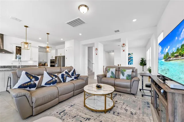 a living room with furniture kitchen view and a chandelier