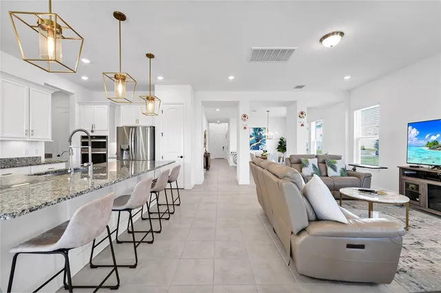 a large kitchen with kitchen island a large counter top space and stainless steel appliances