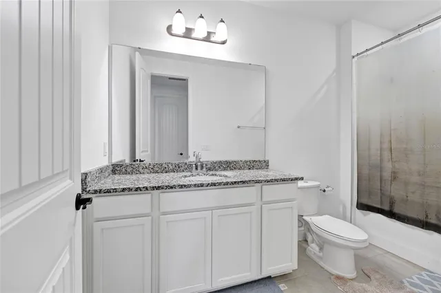 a bathroom with a granite countertop sink a toilet and a mirror