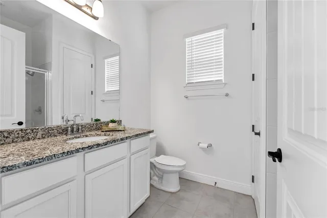 a bathroom with a granite countertop toilet a sink and a mirror