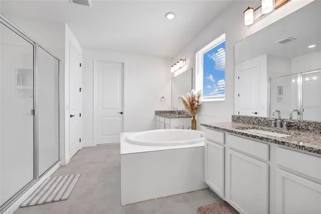 a bathroom with a double vanity sink a mirror and a bathtub