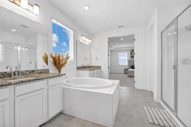 a large bathroom with a granite countertop sink a mirror and a bathtub
