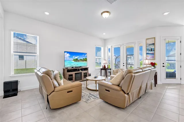a living room with furniture a flat screen tv and a large window