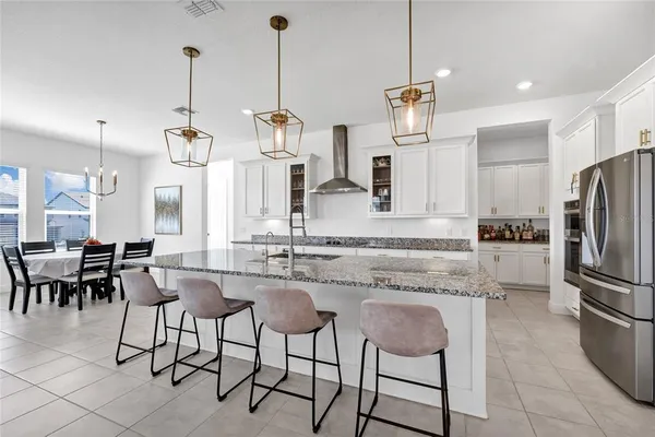 a kitchen with stainless steel appliances kitchen island granite countertop a table chairs and a refrigerator