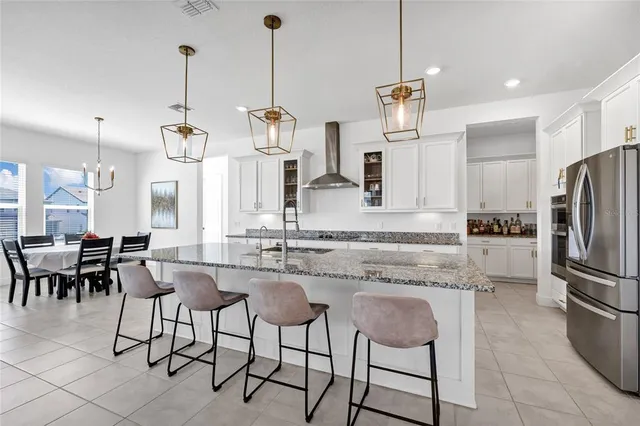 a kitchen with stainless steel appliances kitchen island granite countertop a table chairs and a refrigerator