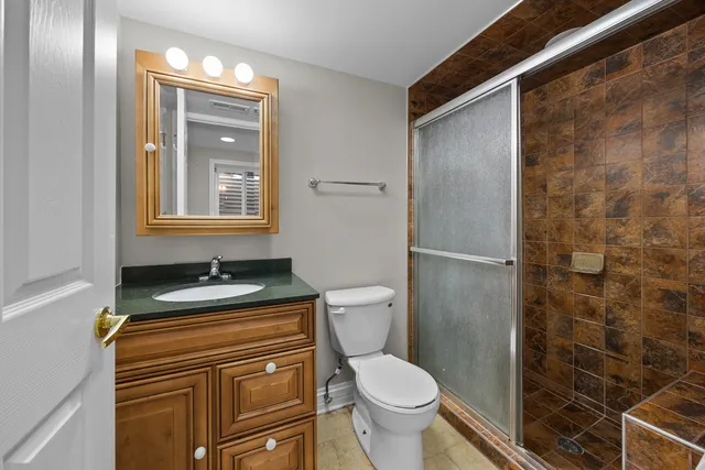 a bathroom with a granite countertop toilet a sink and a shower