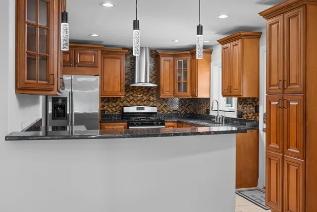 a kitchen with stainless steel appliances granite countertop a refrigerator a sink and wooden cabinets