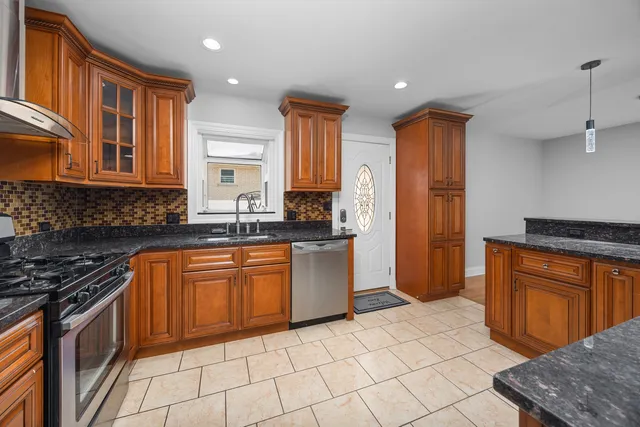 a kitchen with stainless steel appliances granite countertop a stove a sink and a refrigerator