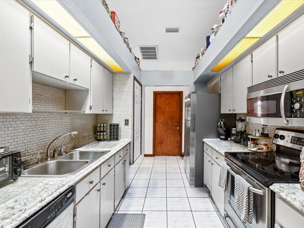 18824 Parade Road Hudson, FL 34667 - Photo 12 of 38 a kitchen with stainless steel appliances granite countertop a sink a stove top oven a counter space and cabinets