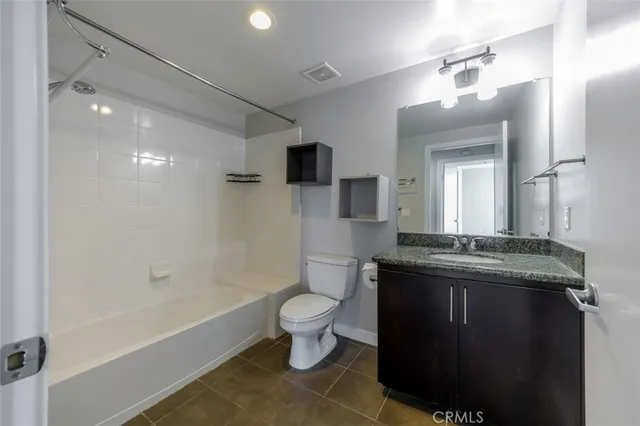 a spacious bathroom with a granite countertop sink a toilet a mirror and bathtub