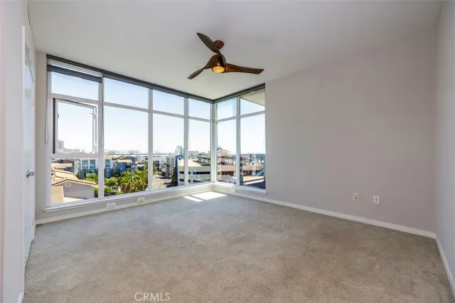 an empty room with chandelier fan windows and city view