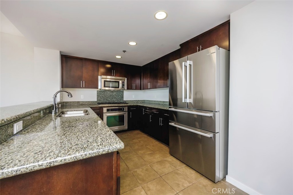 411 West Seaside Way, Unit 703 Long Beach, CA 90802 - Photo 7 of 52 a kitchen with stainless steel appliances granite countertop a sink refrigerator and microwave