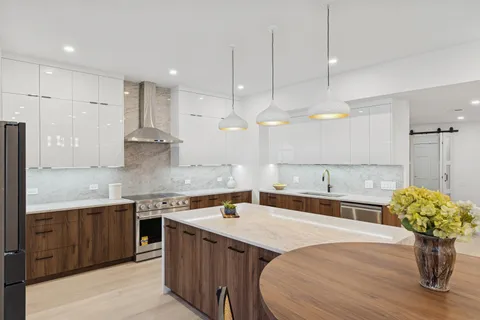 a large kitchen with kitchen island a large counter top a sink stainless steel appliances and cabinets