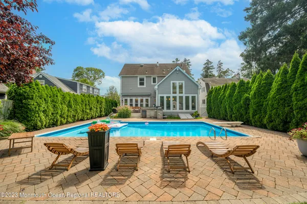 a view of pool with lawn chairs and large trees