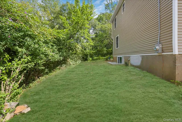 a backyard of a house with plants and large tree