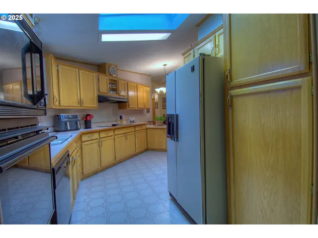 a kitchen with kitchen island granite countertop wooden cabinets a sink a stove a refrigerator and a microwave