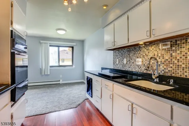 a kitchen with granite countertop a sink stove and cabinets