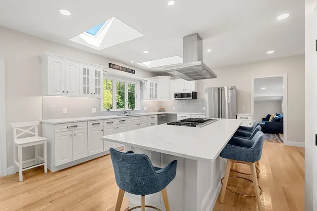 a kitchen with center island white cabinets and stainless steel appliances