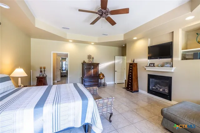 a spacious bedroom with a bed a flat screen tv and a chandelier