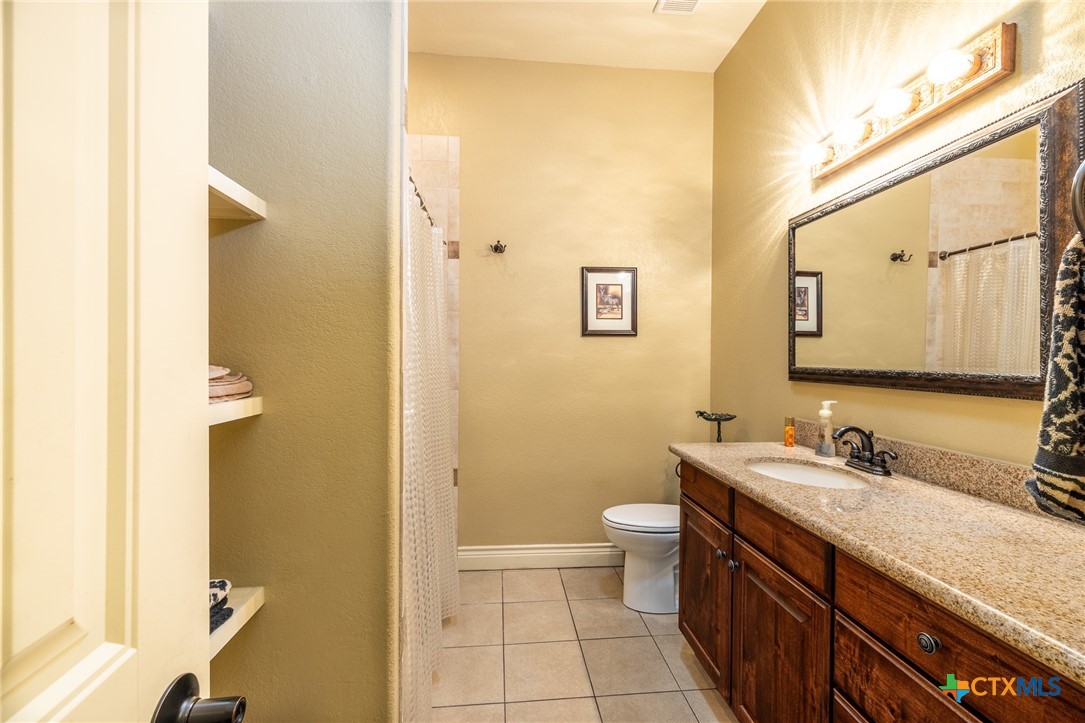 1338 Donovan Street Gonzales, TX 78629 - Photo 18 of 24 a bathroom with a granite countertop sink mirror and a toilet