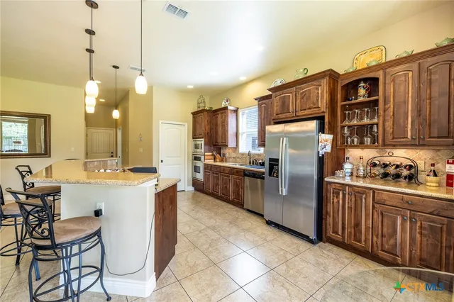 a kitchen with stainless steel appliances granite countertop a stove top oven a sink dishwasher a dining table and chairs with wooden floor