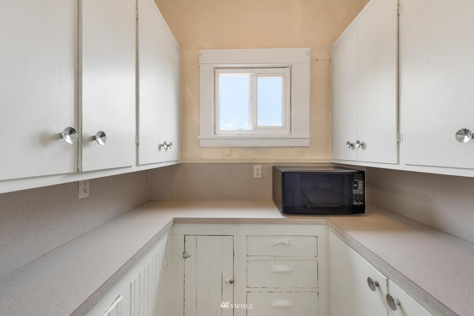 4852 South Orcas Street Seattle, WA 98118 - Photo 12 of 20 a kitchen with granite countertop white cabinets and a window