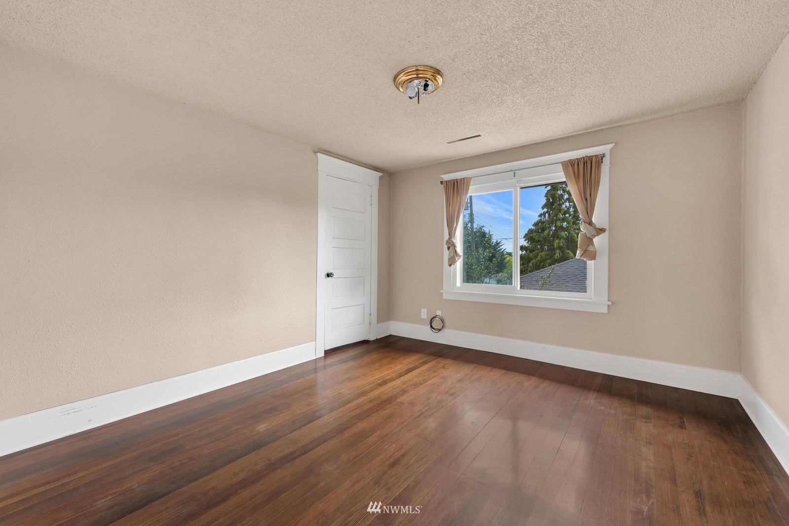 4852 South Orcas Street Seattle, WA 98118 - Photo 14 of 20 a view of an empty room with wooden floor and a window