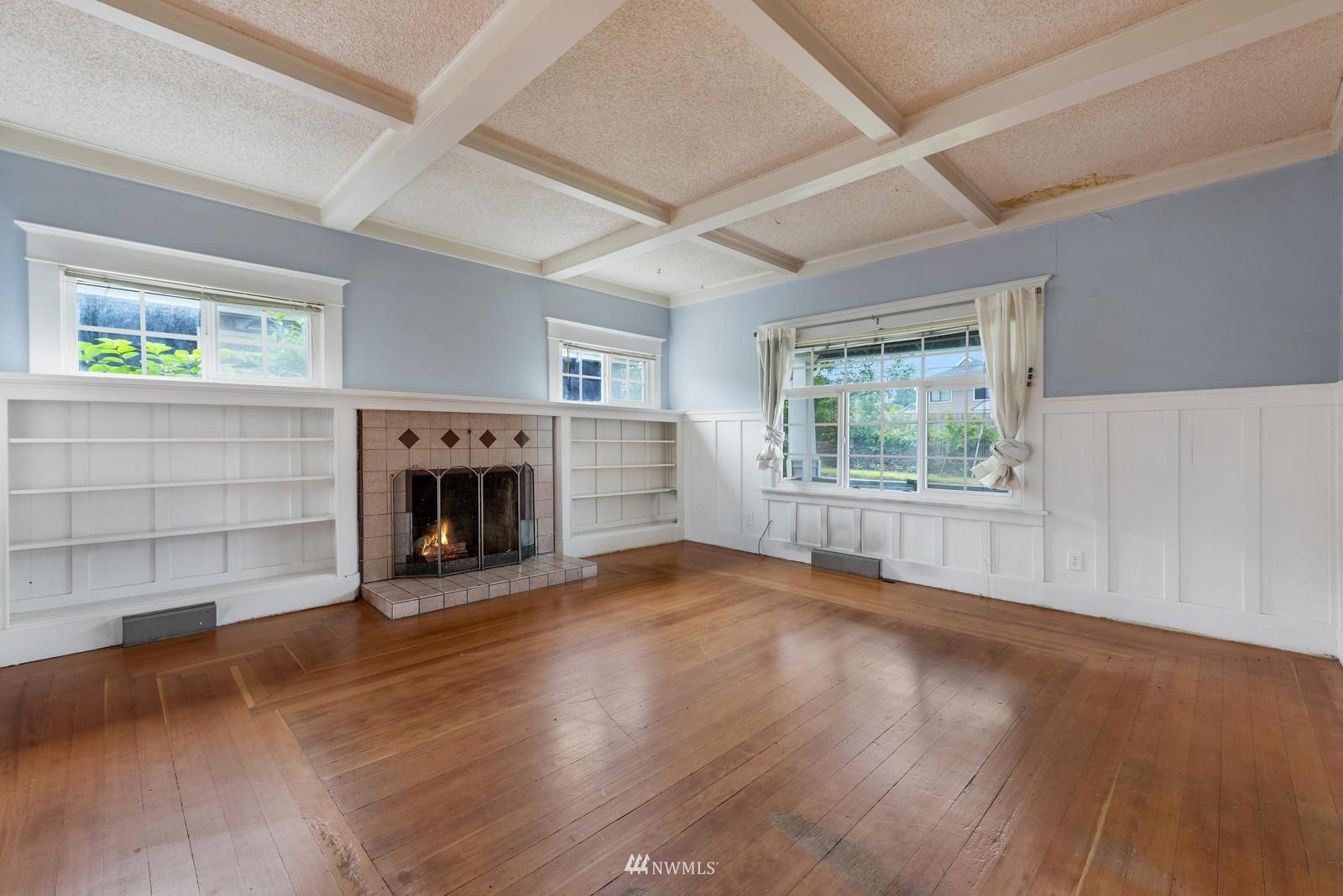 4852 South Orcas Street Seattle, WA 98118 - Photo 6 of 20 an empty room with windows fireplace and wooden floor