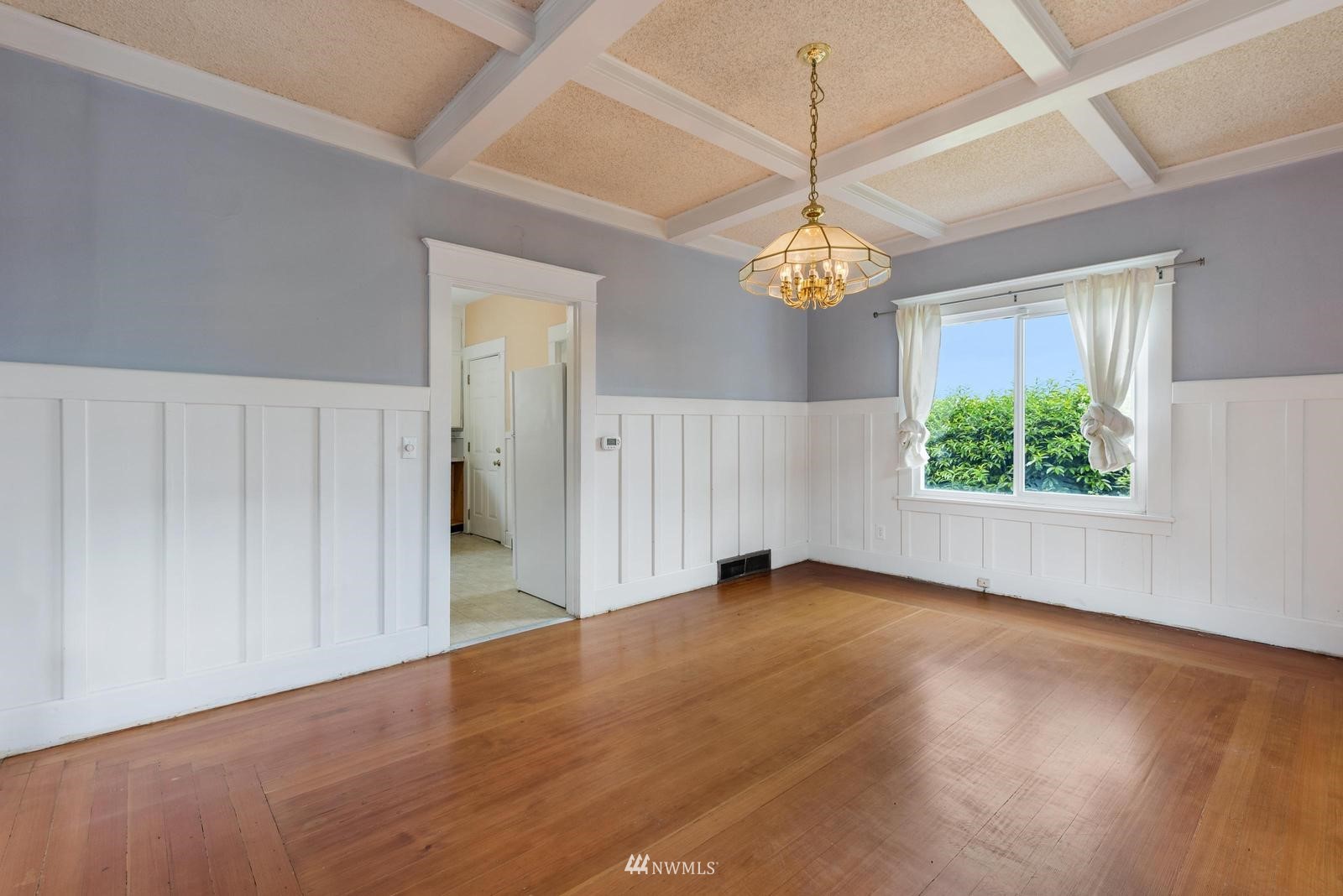 4852 South Orcas Street Seattle, WA 98118 - Photo 7 of 20 an empty room with wooden floor chandelier and windows